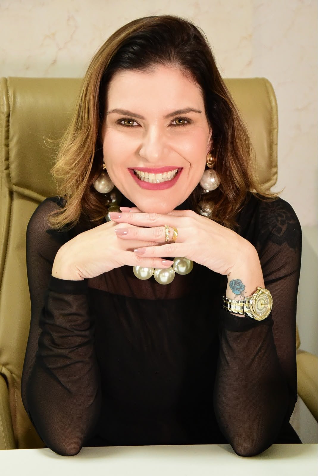 Dra. Ana Carla Prado sorrindo, com as mãos apoiadas sob o rosto